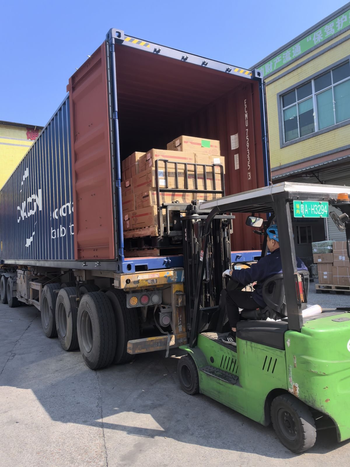 Forklift loading cargo into blue shipping container at Dongguan port
